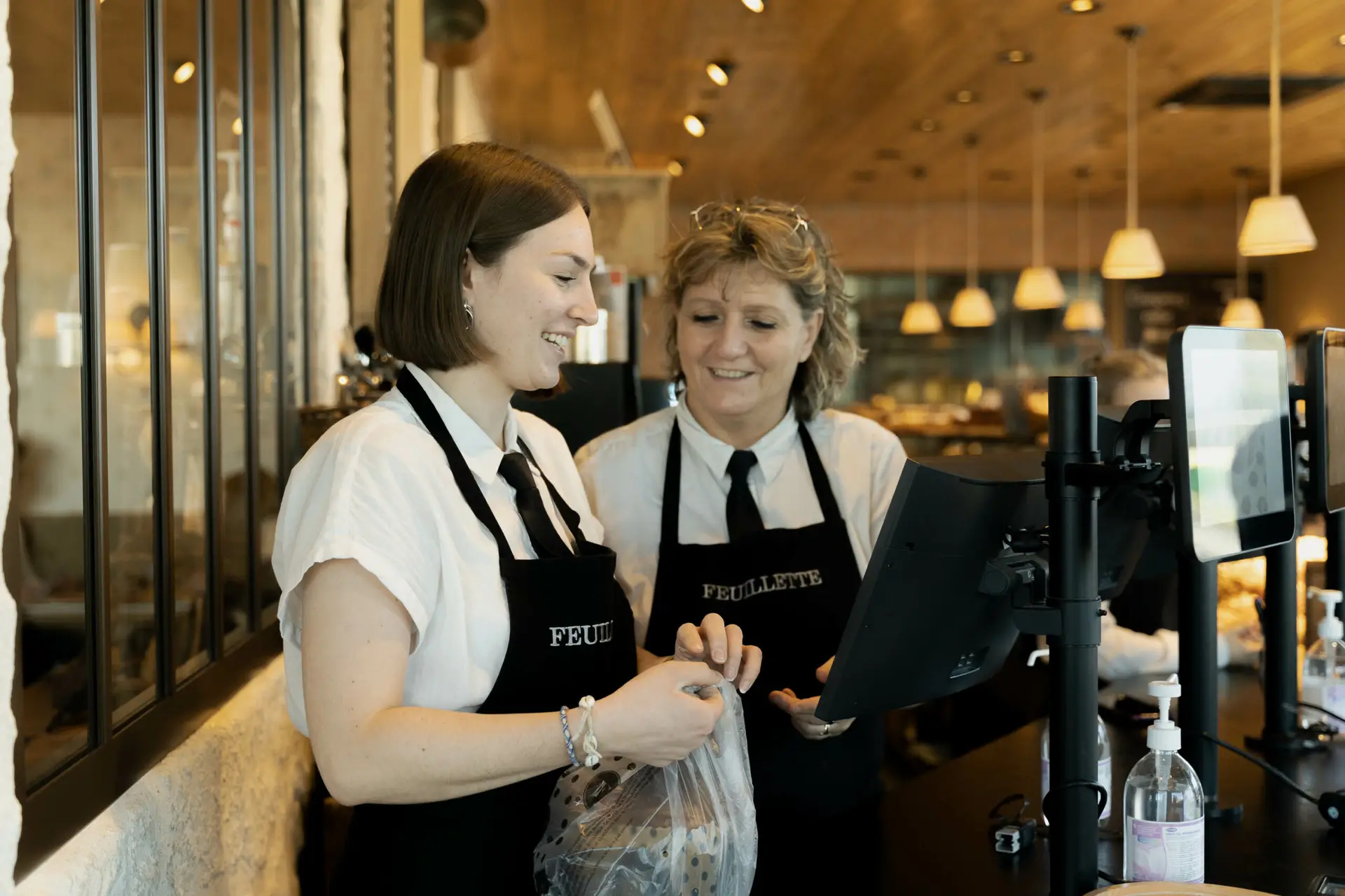 Groupe Ecofac – Métier – Le Mans – Feuillette-17 Photo d'une étudiante Ecofac en alternance dans une boulangerie avec sa responsable à la caisse de la boulangerie.